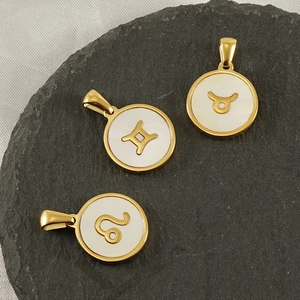 Detailed view of 18K gold plated constellation pendants with white shell inlay on stone