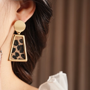 Gros plan d'une boucle d'oreille dorée avec pendentif léopard porté par un mannequin