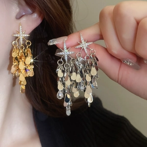 Vue détaillée de boucles d'oreilles étoiles en or et argent avec pompons goutte d'eau
