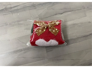 Gros plan d'une chaussette de Noël rouge en tricot avec motifs de cœur sous emballage