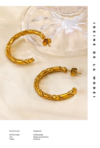 Close-up of gold-plated twisted C-shaped earrings with spiral texture and butterfly backs