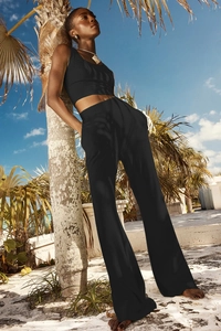 Completo sportivo a coste nero con top corto e pantaloni a gamba larga sulla spiaggia