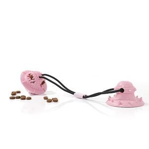 Pink suction cup dog toy with chew ball and food dispenser function on white background