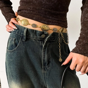 Macro detail of vintage gold chain belt with embossed oval discs on denim jeans