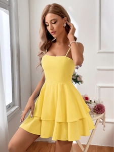 Detailed close-up of yellow cotton mini dress with tiered ruffle skirt and bow waist tie
