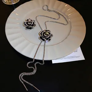 Collier camélia en émail noir avec pompon et zircons sur une assiette en céramique