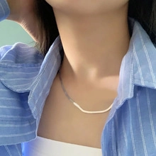 Close-up of minimalist silver snake chain necklace on model neck and collarbone
