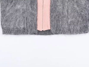 Detail of grey plush knit cardigan with pink ribbed trim and silver metal zipper closure