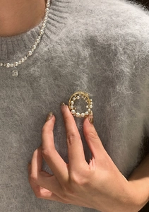Close-up of a 24k gold plated wreath brooch with pearls and sparkling zircons on a sweater