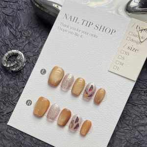Detail of luxury press-on nails featuring golden cat-eye effect and silver glitter accents