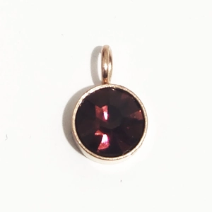 Détail d'un pendentif 6mm en acier doré avec pierre de naissance facettée rouge foncé
