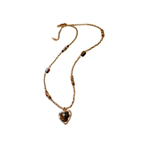Collier vintage avec pendentif cœur marron, perles dorées et pierres œil de tigre sur fond blanc