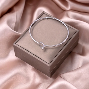 Detail shot of silver knot heart bangle on champagne jewelry box with silk background