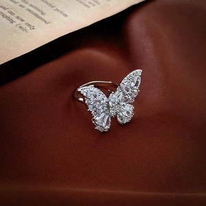 Macro shot of silver butterfly ring with cubic zirconia stones on silk fabric background