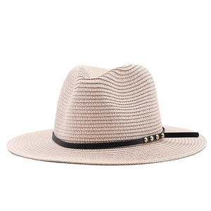 Close-up of beige woven straw hat featuring black leather band with golden metal rivets