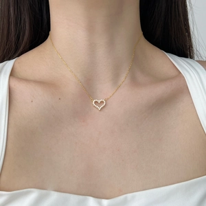 Close-up of elegant gold heart pendant necklace with shimmering zircons on a model