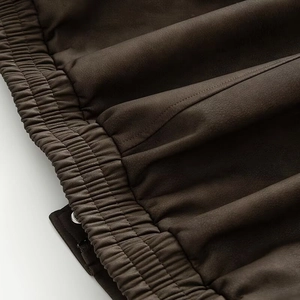 Detail of dark brown faux suede jacket featuring elastic cuffs and precise stitching