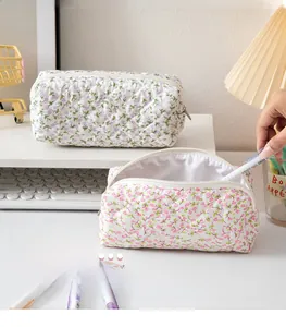 Detail of floral quilted pencil cases with zipper opening in purple and pink patterns