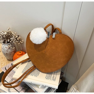 Detail der herzförmigen Wildledertasche in Karamellbraun mit weißem Plüsch-Anhänger