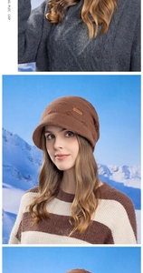 Close-up of brown knit beanie with brim featuring a leather logo patch in a snowy setting