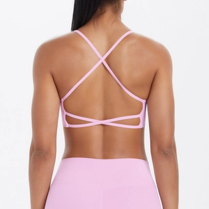 Vue détaillée du dos d'un soutien-gorge de yoga rose avec de fines bretelles croisées