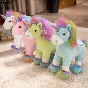Plush unicorn toys in pink, white, green, and blue with rainbow manes on soft carpet