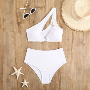 Detailed flat lay of white ribbed bikini with single shoulder strap and gold metal rings