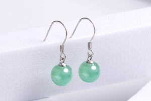 Detail of elegant silver drop earrings featuring polished round green aventurine beads