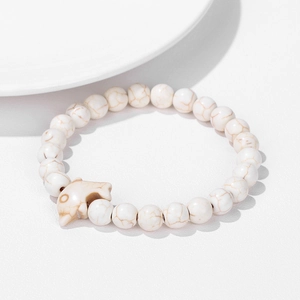 Close-up of natural white turquoise beaded bracelet featuring a dolphin-shaped charm detail