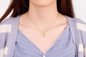 Detailed view of a gold elephant necklace with hollow flower design on a female model