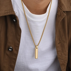 Close-up of golden geometric rectangle pendant necklace worn on a male model