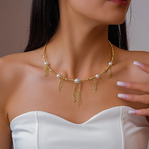 Detail of gold beaded necklace with pearls and fringe tassels on female neck
