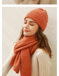 Detail von warmem orangefarbenem Strickmützen- und Schal-Set aus weichem Wollgewebe