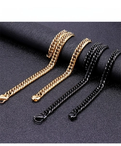 Close-up of gold and black Cuban link necklaces with lobster clasps on a display stand