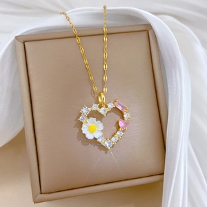 Detailaufnahme der goldenen Herz-Halskette mit Gänseblümchen und Zirkonia auf Seide