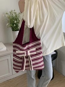 Detail of the knit tote bag featuring a purple striped pattern and a large bow decoration
