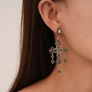 Vue détaillée de boucles d'oreilles croix baroques avec perles et cristaux sur un modèle