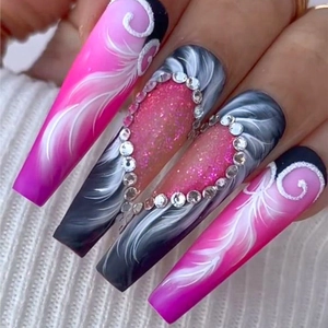Close-up of pink and black gradient fake nails with rhinestone heart and feather patterns