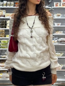 White off-shoulder sweater with cable knit texture shown in a casual street style look