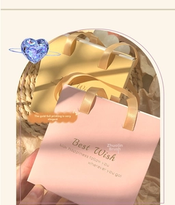 Sacs cadeaux en papier rose et jaune avec marquage à l'or et poignées en ruban