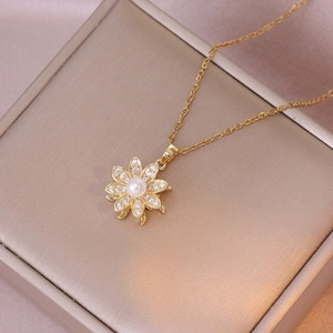 Elegant gold spinning sunflower necklace with pearl and zircon inlay on a jewelry box