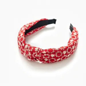 Red embroidered wide headband with white floral patterns and central knot for women