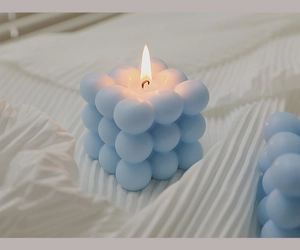 Macro shot of a burning sky blue bubble cube candle with soy wax matte texture