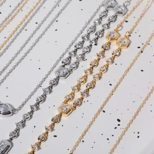 Detail of elegant gold and silver necklaces featuring zircon pendants on a marble surface