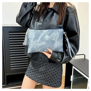 Detail of blue denim textured clutch bag with matching wrist strap and tassel zipper