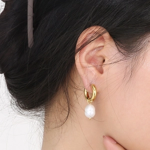 Nahaufnahme eines goldenen Vintage-Ohrrings mit natürlicher Süßwasserperle am Ohr