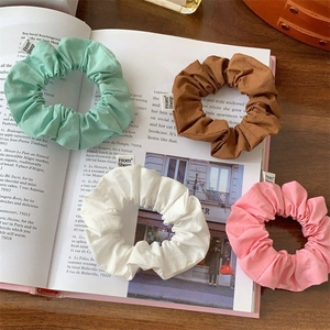 Set of four colorful fabric scrunchies in green brown white and pink on an open book