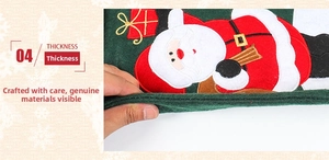 Detail view of thick green linen Christmas stocking with Santa embroidery and gift box decor
