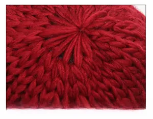 Detailed view of the radial stitching and thick knit texture on top of the red winter hat