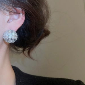 Close-up of sparkling cubic zirconia spherical stud earrings worn on model's ear